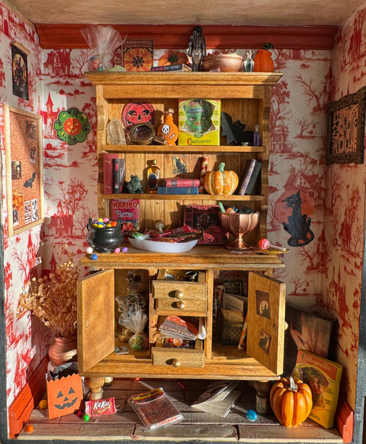 A miniature Halloween-themed diorama featuring a room full of festive candy, games, and spooky wall decorations.